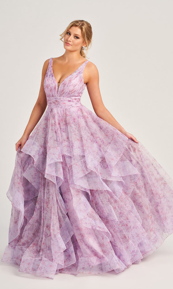 A woman wears the Colette Tiered Long Print Prom Ball Gown CL5273, a sleeveless, floor-length lilac floral dress with layered ruffles, standing against a plain light background.